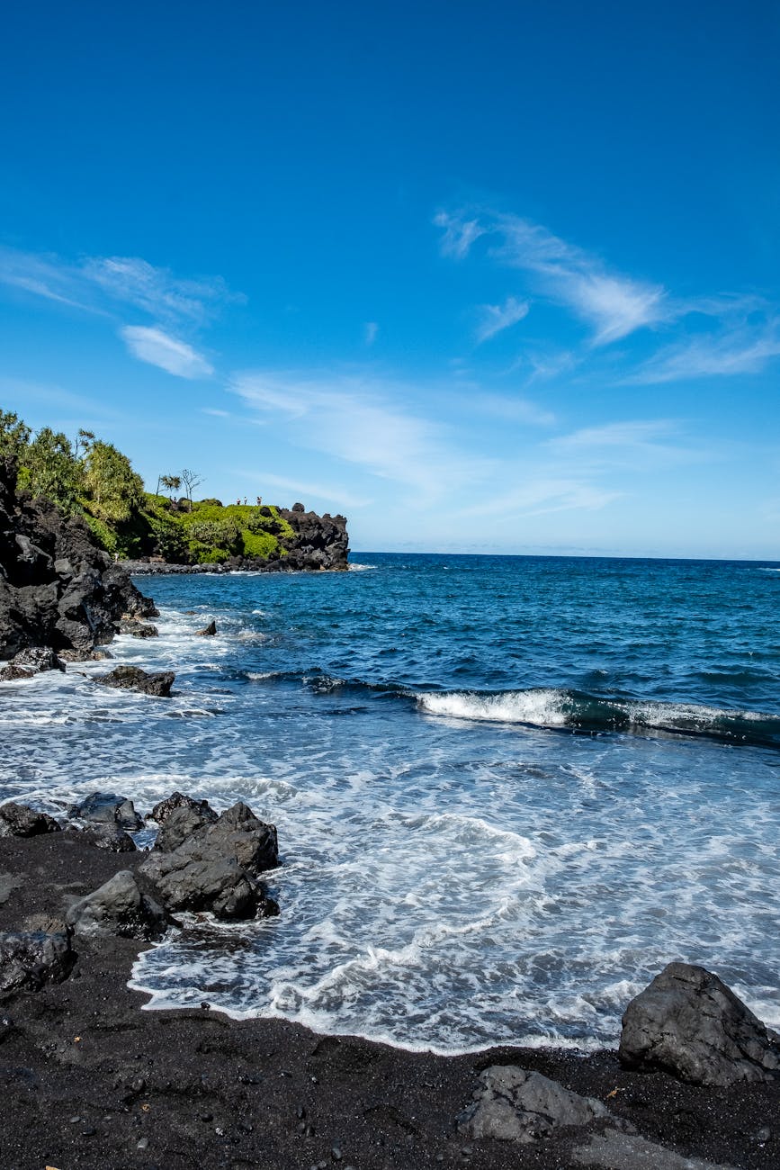 crashing ocean waves on rocky shore under the blue sky